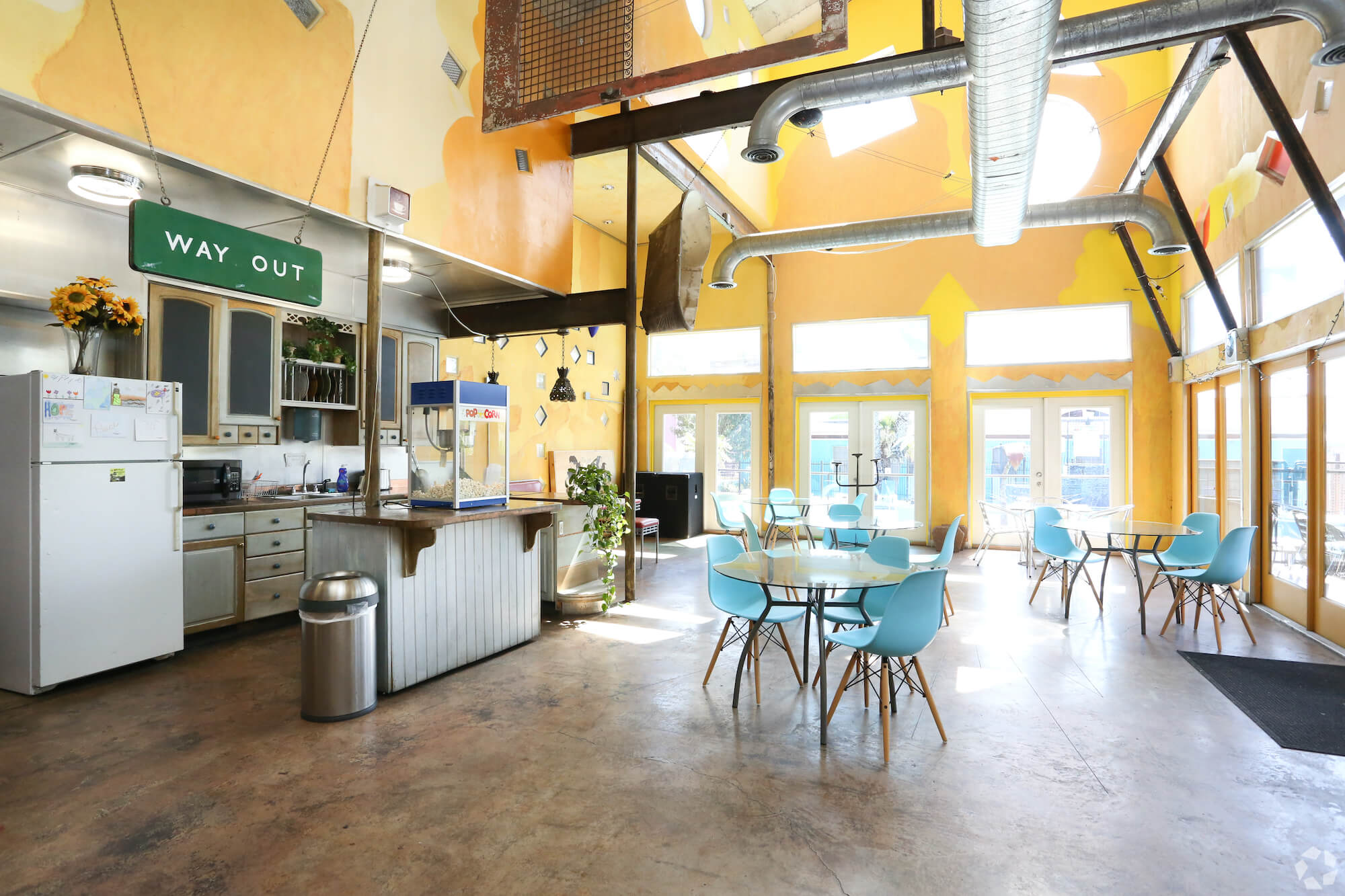 The inside of the club at The Metropolis Apartments with kitchenette and spread out tables